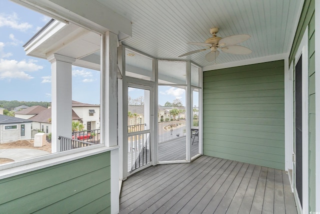 unfurnished sunroom with a residential view and a ceiling fan