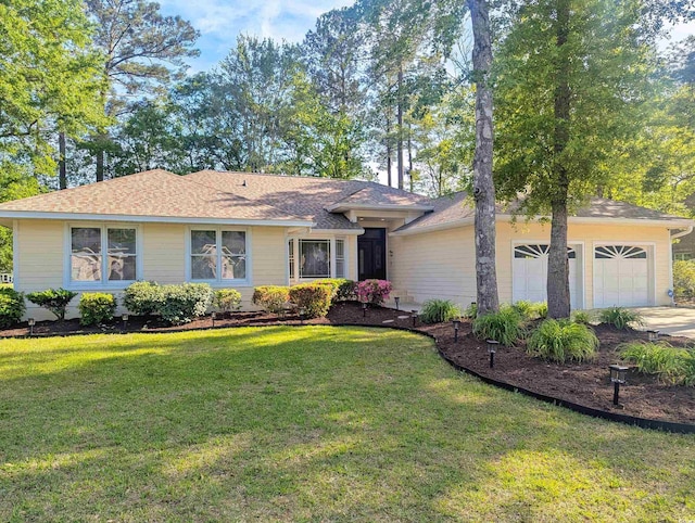 view of front of house featuring a garage, a front lawn, driveway, and a shingled roof