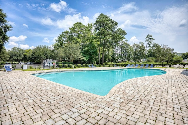 pool with a patio area and fence