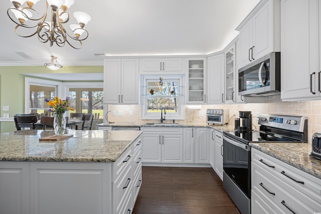 kitchen with appliances with stainless steel finishes, a sink, a chandelier, white cabinetry, and ornamental molding