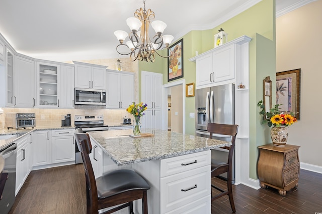 kitchen featuring stainless steel appliances, a kitchen breakfast bar, backsplash, a kitchen island, and white cabinets