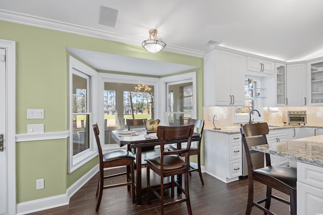 dining area with dark wood finished floors, plenty of natural light, baseboards, and ornamental molding