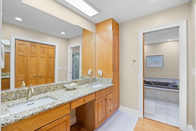 full bathroom with wood finished floors, baseboards, double vanity, a garden tub, and an enclosed shower