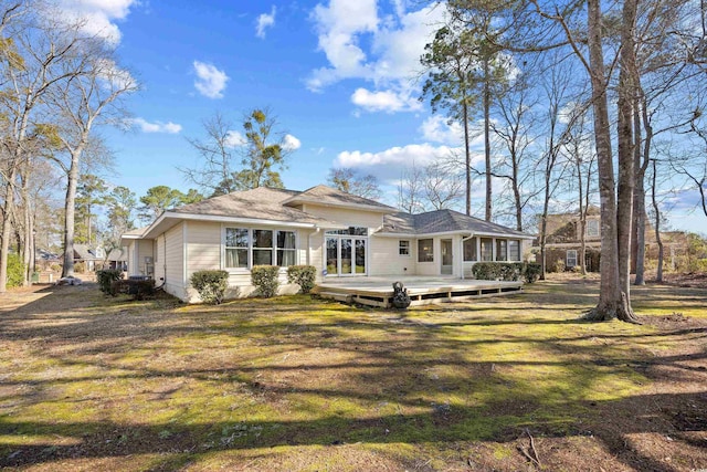 back of property with a wooden deck and a lawn