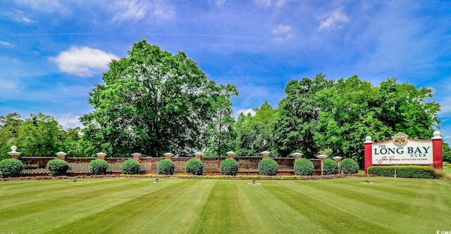 view of green lawn featuring view of golf course and view of wooded area