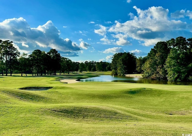 view of home's community with a water view, golf course view, and a lawn