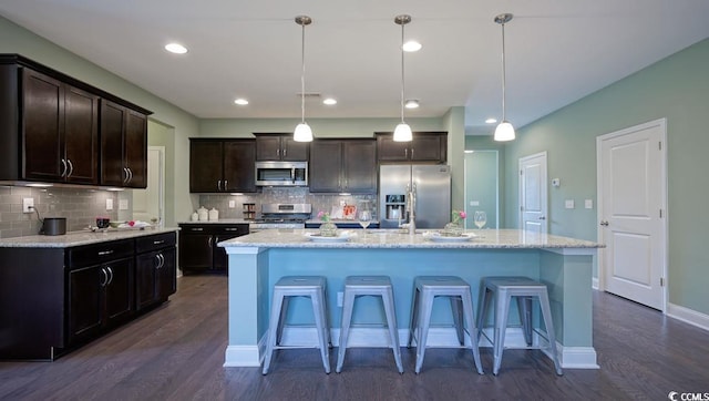 kitchen with stainless steel appliances, dark wood-style floors, tasteful backsplash, a kitchen breakfast bar, and recessed lighting