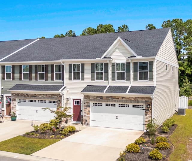 view of front of home featuring concrete driveway, a garage, stone siding, and a shingled roof