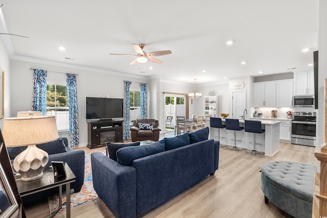 living room with ceiling fan with notable chandelier, crown molding, light wood-style flooring, and recessed lighting