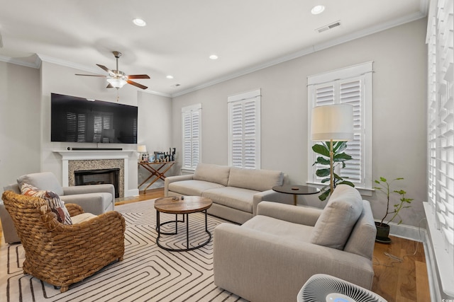 living room with visible vents, wood finished floors, ornamental molding, and a ceiling fan