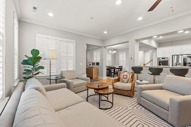 living room with recessed lighting, crown molding, and ceiling fan with notable chandelier