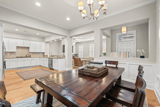 dining area featuring a decorative wall, wine cooler, ornamental molding, and light wood finished floors