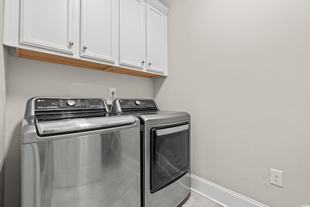 washroom with tile patterned floors, baseboards, cabinet space, and separate washer and dryer