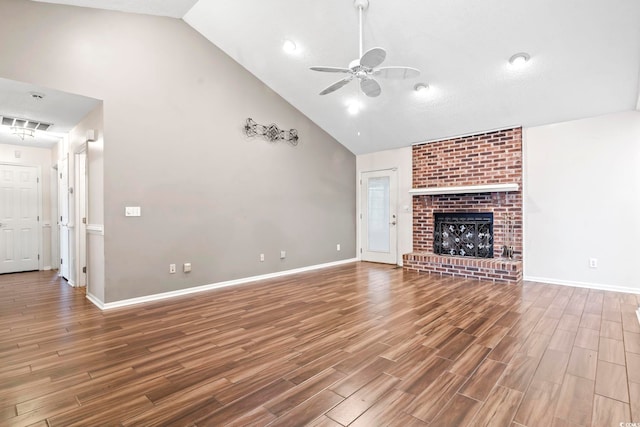 unfurnished living room featuring a brick fireplace, baseboards, ceiling fan, wood finished floors, and high vaulted ceiling