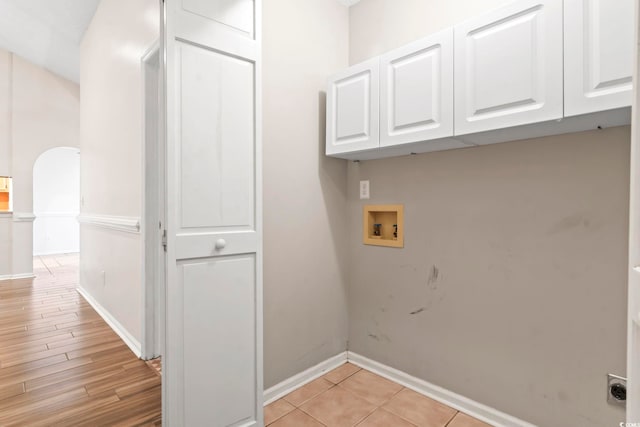 washroom featuring electric dryer hookup, washer hookup, cabinet space, arched walkways, and baseboards