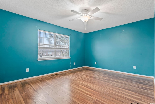 unfurnished room featuring baseboards, a textured ceiling, wood finished floors, and a ceiling fan