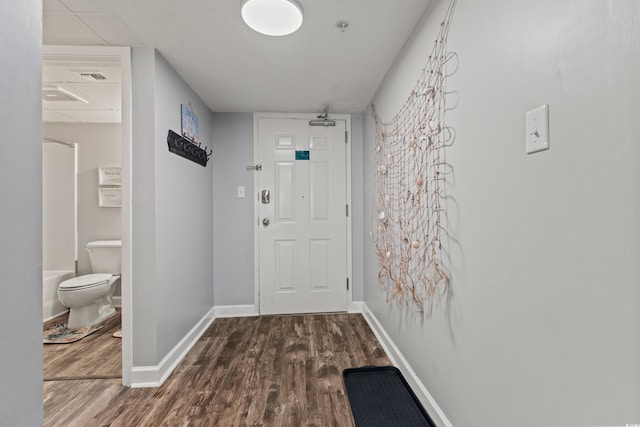 hallway featuring dark wood finished floors, visible vents, and baseboards