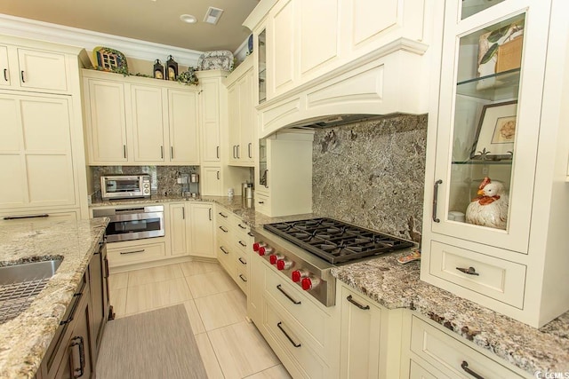 kitchen with tasteful backsplash, visible vents, glass insert cabinets, a toaster, and stainless steel appliances