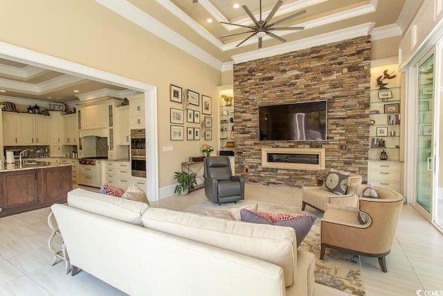 living area featuring light tile patterned floors, a tray ceiling, ornamental molding, and ceiling fan