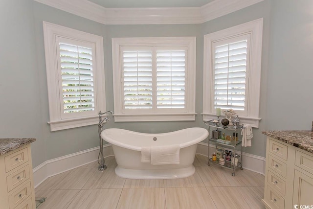 bathroom featuring crown molding, baseboards, a freestanding tub, tile patterned floors, and vanity