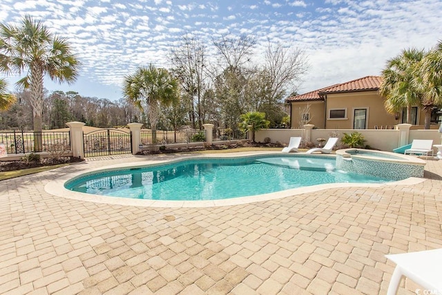 view of pool featuring a patio, fence, and a pool with connected hot tub