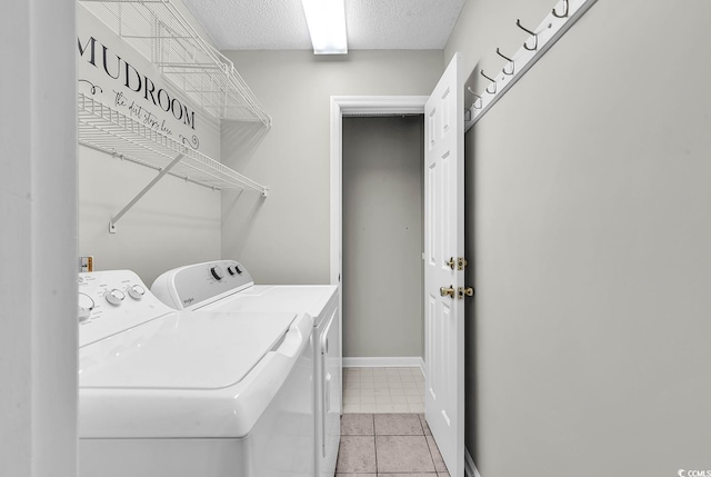 laundry room with light tile patterned floors, baseboards, laundry area, a textured ceiling, and washer and dryer