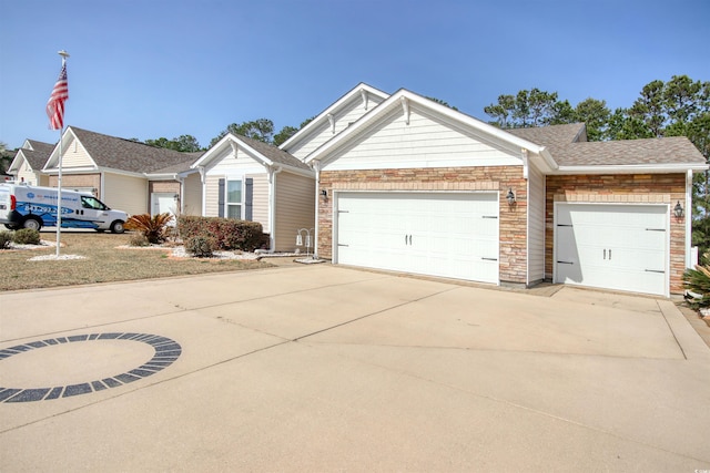 ranch-style house featuring concrete driveway, an attached garage, stone siding, and roof with shingles