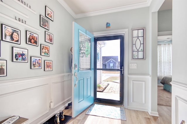 entrance foyer featuring a decorative wall, light wood-style floors, wainscoting, and ornamental molding