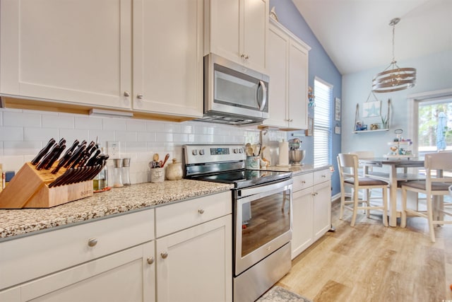 kitchen featuring backsplash, vaulted ceiling, light wood-style flooring, white cabinets, and stainless steel appliances