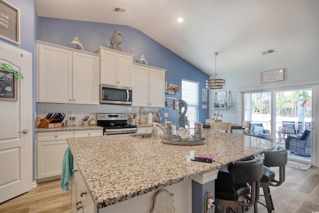 kitchen with a kitchen breakfast bar, light wood-style floors, visible vents, and appliances with stainless steel finishes