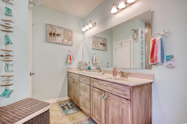 full bath featuring tile patterned flooring, double vanity, baseboards, and a sink