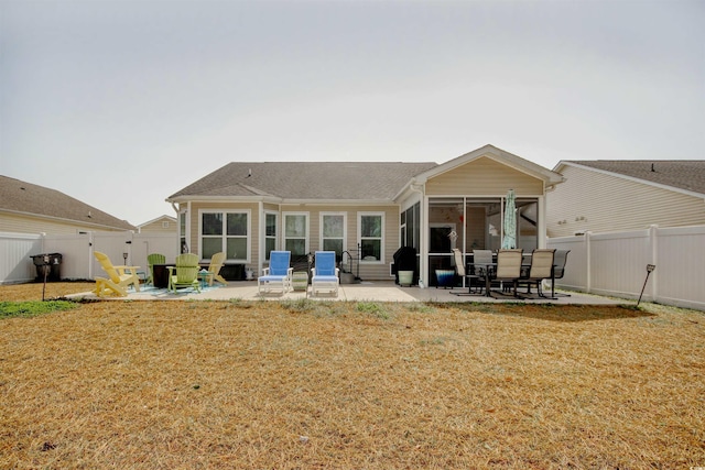 back of property with a yard, a sunroom, a fenced backyard, and a patio area