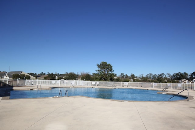 community pool with a patio and fence