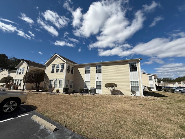 view of home's exterior with a lawn and uncovered parking