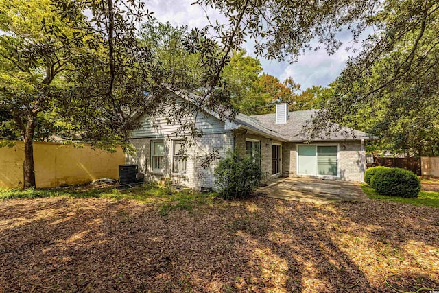 back of property featuring a patio, fence, central AC, a chimney, and brick siding