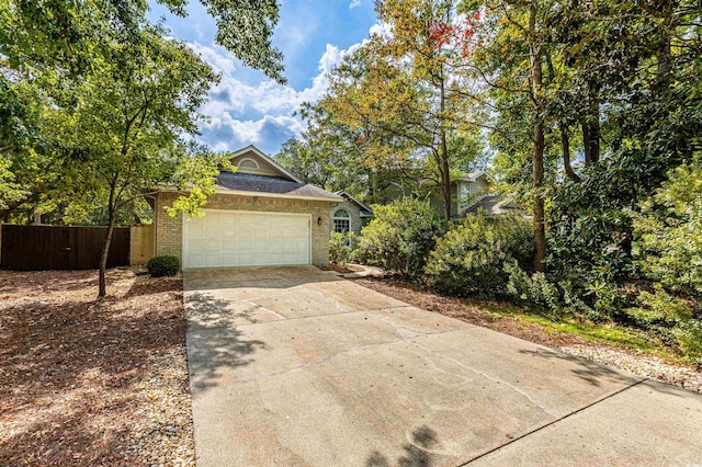 view of front of property featuring brick siding, concrete driveway, an attached garage, and fence