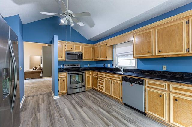 kitchen with light wood-type flooring, a sink, stainless steel appliances, ceiling fan, and vaulted ceiling