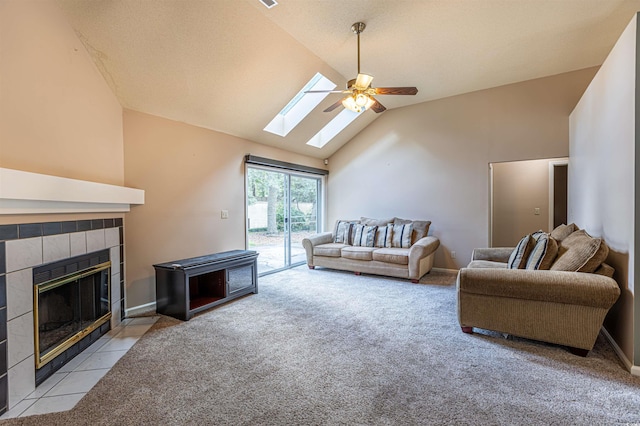 living area featuring baseboards, a tiled fireplace, light colored carpet, high vaulted ceiling, and a ceiling fan