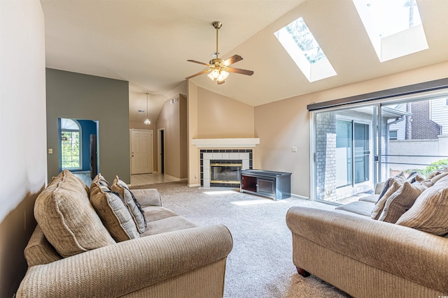 living room featuring baseboards, ceiling fan, a tiled fireplace, light colored carpet, and high vaulted ceiling