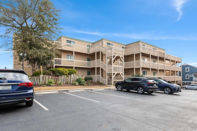 view of building exterior with uncovered parking and fence