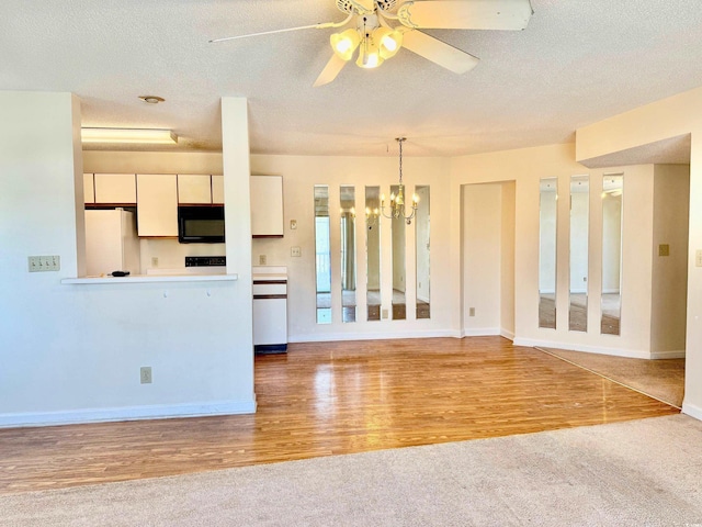 kitchen featuring pendant lighting, wood finished floors, freestanding refrigerator, white cabinets, and black microwave