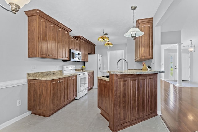 kitchen with white appliances, light stone counters, a peninsula, a sink, and pendant lighting