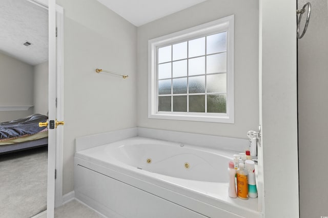 ensuite bathroom featuring visible vents, connected bathroom, and a whirlpool tub