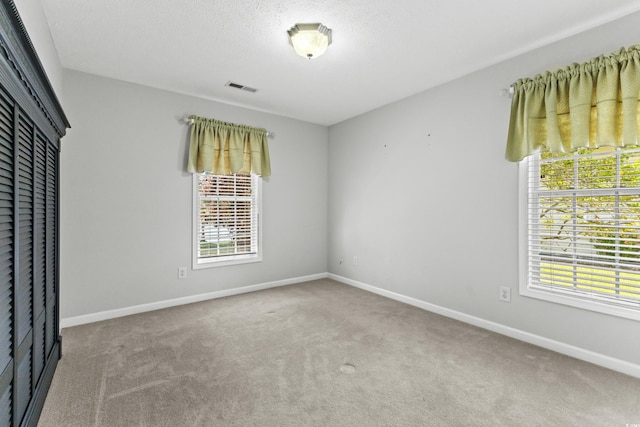 unfurnished bedroom featuring visible vents, a textured ceiling, a closet, carpet flooring, and baseboards