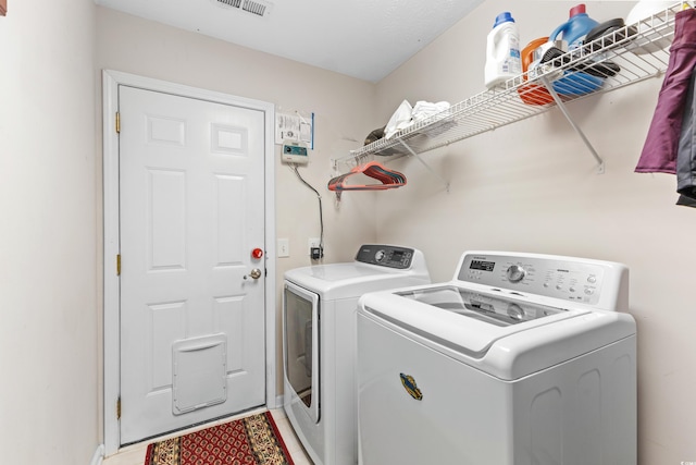 laundry area with laundry area, visible vents, and washing machine and clothes dryer