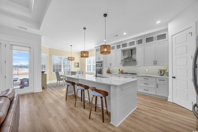 kitchen featuring light wood-type flooring, tasteful backsplash, a breakfast bar area, and wall chimney exhaust hood