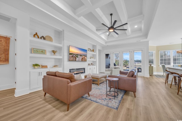 living area with beamed ceiling, coffered ceiling, a fireplace, light wood finished floors, and ceiling fan