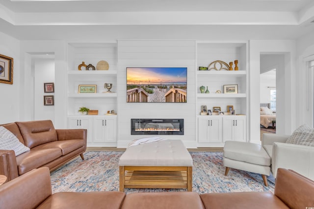 living room with built in features, light wood-style floors, and a fireplace