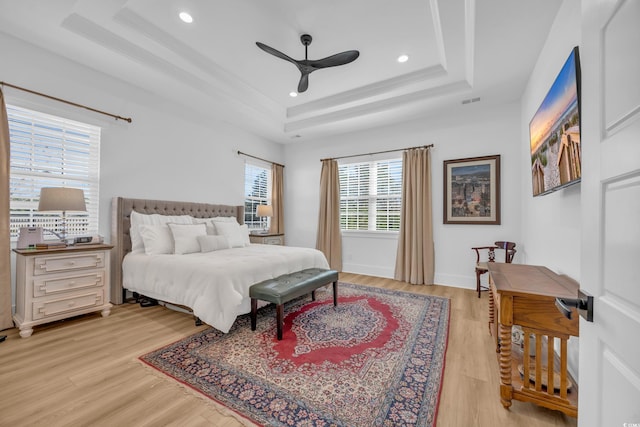 bedroom with baseboards, a tray ceiling, ornamental molding, recessed lighting, and light wood-style floors