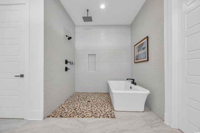 full bath with a soaking tub, tile walls, visible vents, and tiled shower